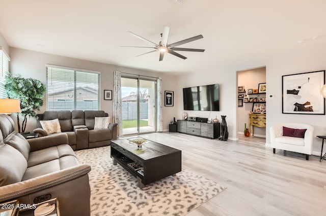 living area featuring light wood finished floors, baseboards, and a ceiling fan