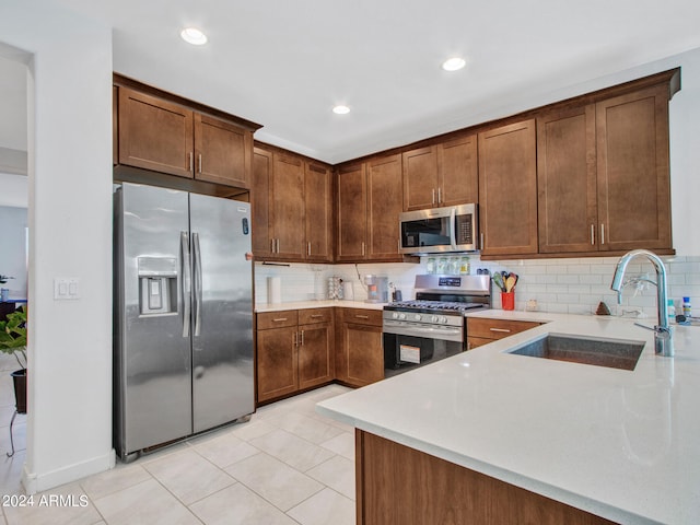 kitchen with appliances with stainless steel finishes, decorative backsplash, sink, and light tile patterned flooring