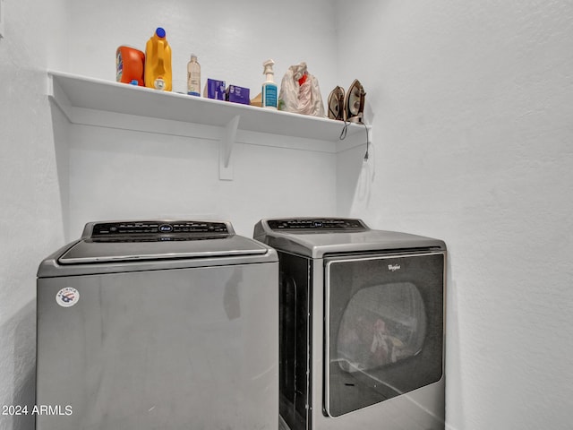 washroom with laundry area, washing machine and clothes dryer, and a textured wall
