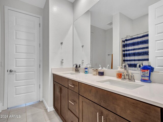 bathroom featuring a sink, visible vents, double vanity, and tile patterned flooring