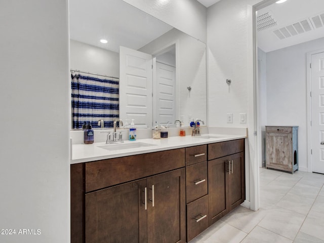 bathroom with a sink, visible vents, double vanity, and tile patterned flooring