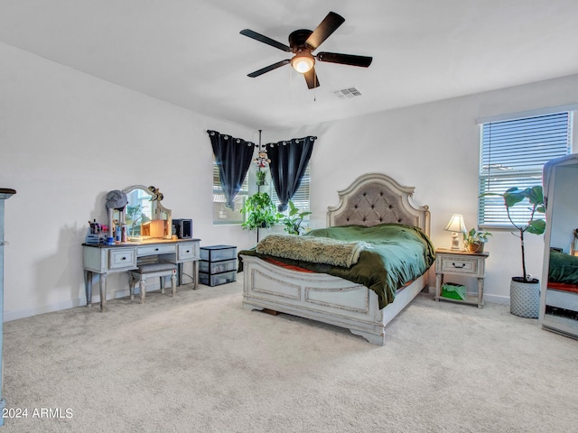 carpeted bedroom with a ceiling fan and visible vents