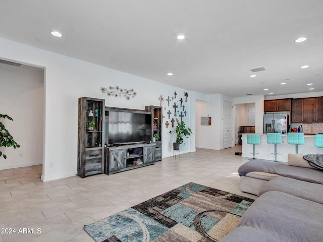 living area featuring recessed lighting, light tile patterned floors, visible vents, and baseboards
