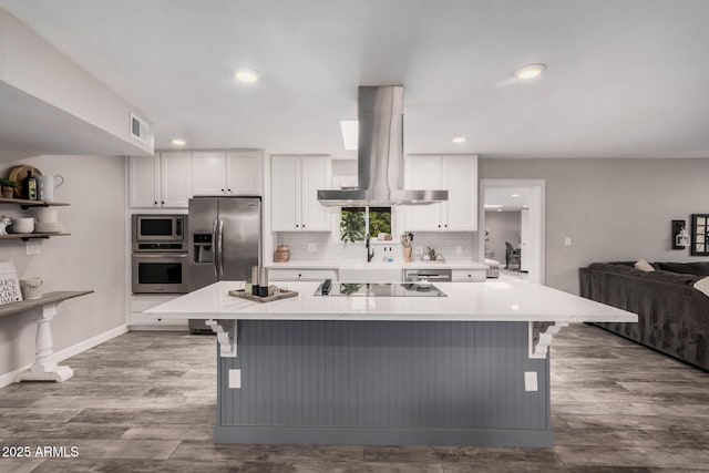 kitchen featuring island exhaust hood, visible vents, a kitchen breakfast bar, and appliances with stainless steel finishes