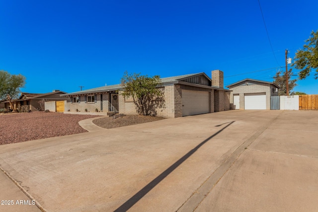 view of front of home with fence, a chimney, concrete driveway, a garage, and brick siding