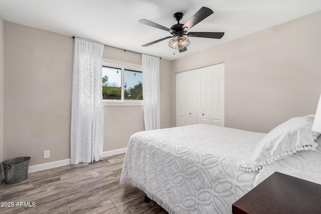 bedroom featuring ceiling fan, a closet, baseboards, and wood finished floors