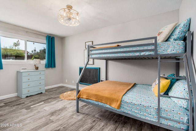 bedroom featuring a notable chandelier, baseboards, and wood finished floors