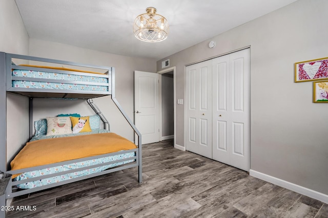 bedroom featuring visible vents, baseboards, a chandelier, wood finished floors, and a closet