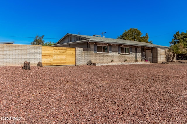 exterior space featuring fence, brick siding, and roof with shingles