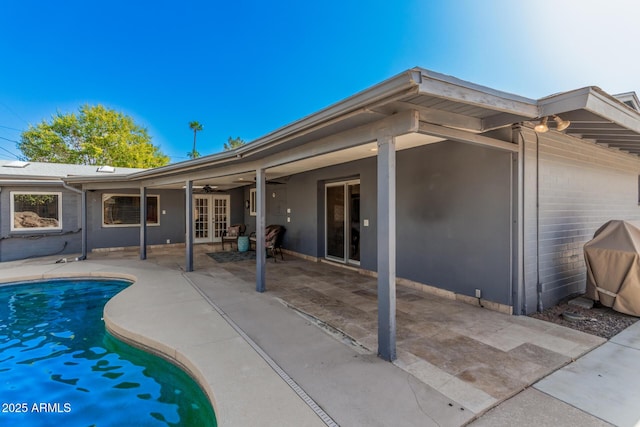 rear view of property with an outdoor pool, french doors, a patio, and ceiling fan