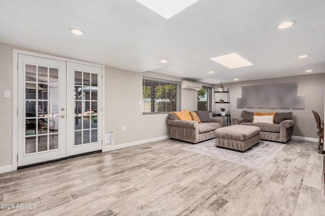 living room with french doors, a skylight, a wall mounted AC, and wood finished floors