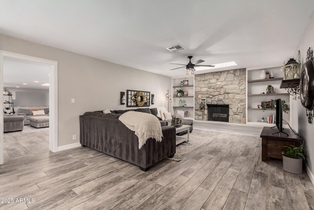 living area with wood finished floors, baseboards, visible vents, a fireplace, and ceiling fan