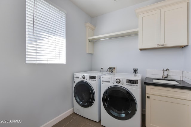 laundry area with cabinets, dark tile patterned flooring, washing machine and clothes dryer, and sink