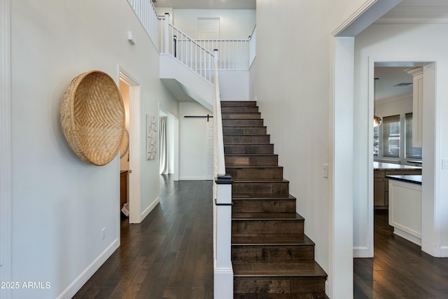 stairs with a towering ceiling, hardwood / wood-style floors, a barn door, and crown molding