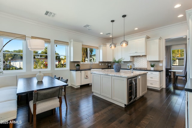 kitchen featuring white cabinetry, hanging light fixtures, and wine cooler