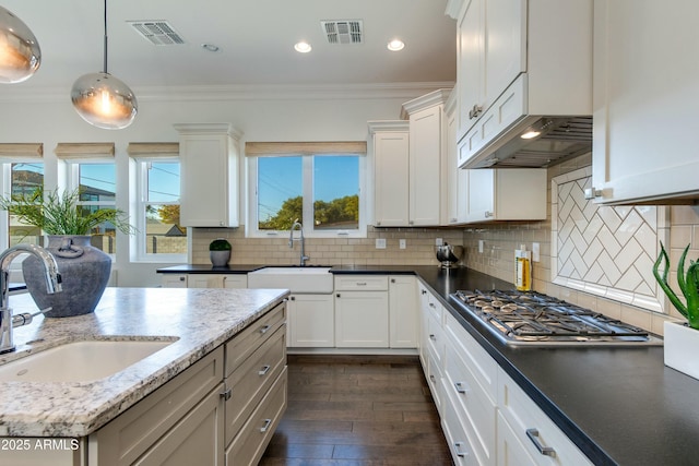 kitchen with decorative backsplash, white cabinetry, hanging light fixtures, and ornamental molding