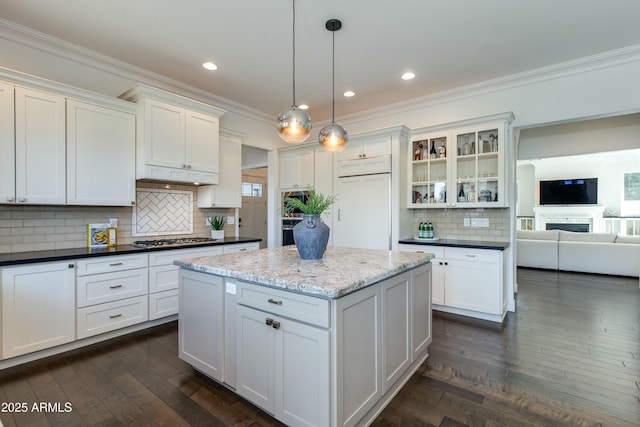 kitchen with backsplash, stainless steel gas cooktop, decorative light fixtures, paneled built in fridge, and white cabinetry