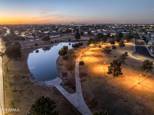 aerial view at dusk featuring a water view