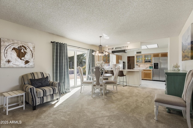 dining room featuring a textured ceiling, a chandelier, and light colored carpet