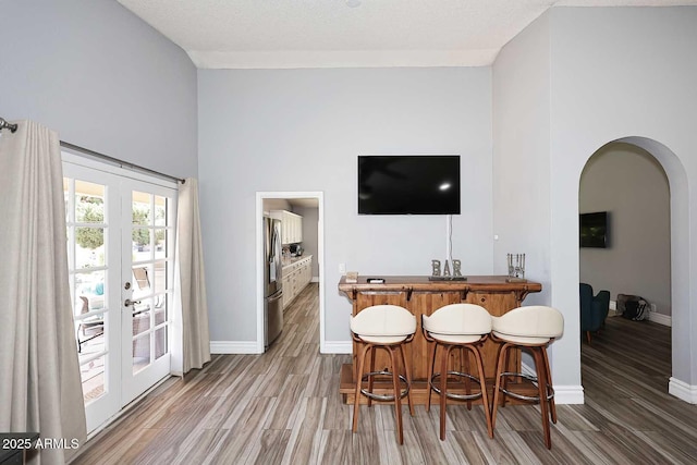 4609 E Monte Cristo Ave, Phoenix, AZ 85032 - bar with arched walkways, stainless steel refrigerator with ice dispenser, wood finished floors, baseboards, and a towering ceiling