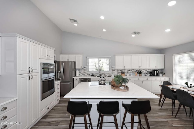 4609 E Monte Cristo Ave, Phoenix, AZ 85032 - kitchen with appliances with stainless steel finishes, vaulted ceiling, tasteful backsplash, a sink, and a breakfast bar