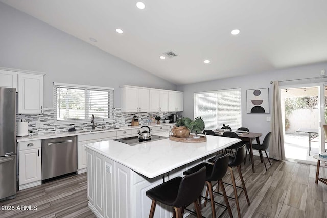 4609 E Monte Cristo Ave, Phoenix, AZ 85032 - kitchen featuring appliances with stainless steel finishes, a sink, decorative backsplash, a breakfast bar, and white cabinetry