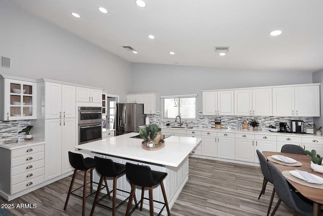 4609 E Monte Cristo Ave, Phoenix, AZ 85032 - kitchen with stainless steel appliances, high vaulted ceiling, decorative backsplash, a breakfast bar area, and white cabinets