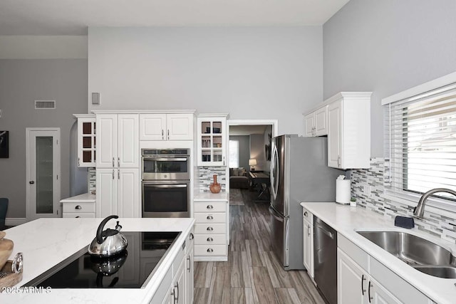 4609 E Monte Cristo Ave, Phoenix, AZ 85032 - kitchen with a sink, stainless steel appliances, a high ceiling, white cabinets, and decorative backsplash