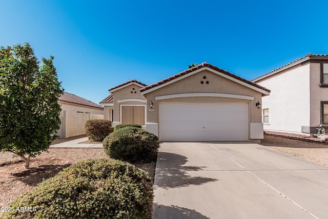 mediterranean / spanish-style home with driveway, a tiled roof, an attached garage, and stucco siding