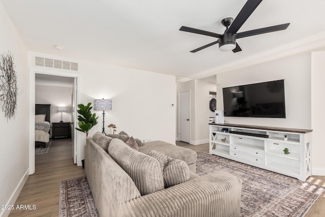 living area with baseboards, a ceiling fan, and wood finished floors