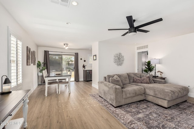 living area featuring light wood-style flooring, visible vents, and baseboards