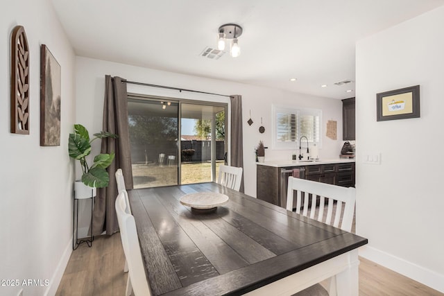 dining space with light wood finished floors, visible vents, and baseboards