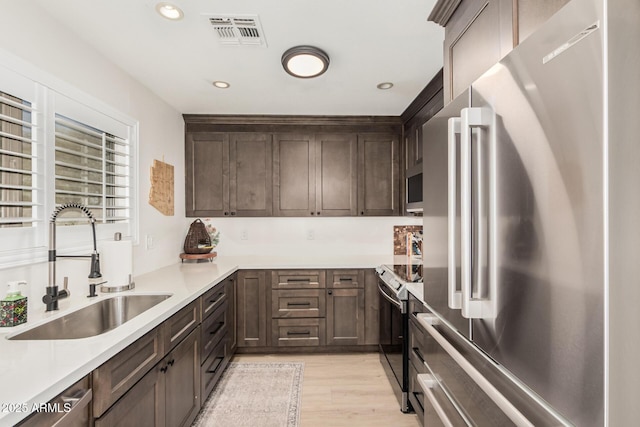 kitchen featuring stainless steel appliances, light countertops, visible vents, and a sink