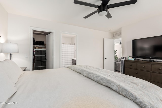 bedroom featuring a walk in closet, a closet, visible vents, ensuite bathroom, and a ceiling fan