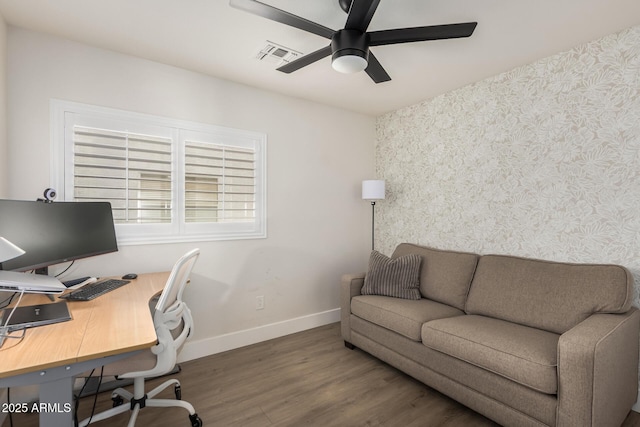 home office with visible vents, ceiling fan, wood finished floors, baseboards, and wallpapered walls