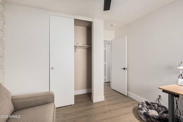 bedroom featuring a closet, ceiling fan, baseboards, and wood finished floors