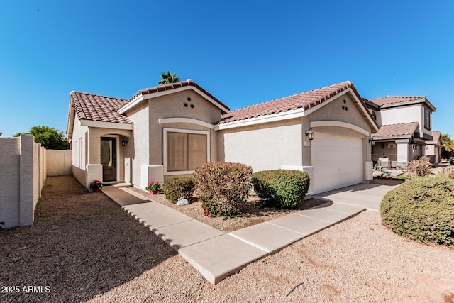 mediterranean / spanish-style house featuring an attached garage, a tile roof, fence, and stucco siding