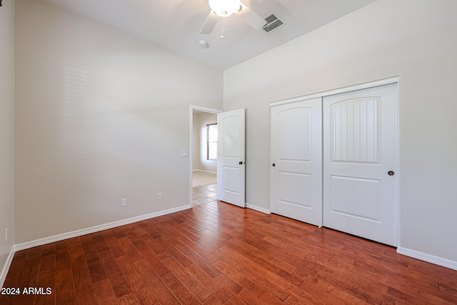 unfurnished bedroom with ceiling fan, a closet, high vaulted ceiling, and wood-type flooring