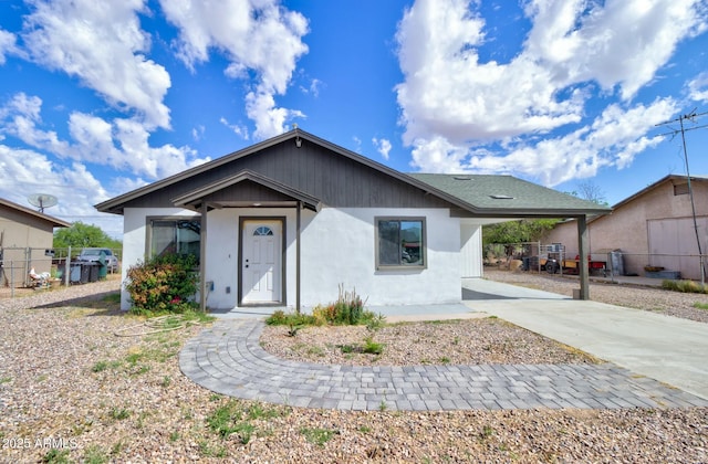 view of front facade with fence, stucco siding, and concrete driveway
