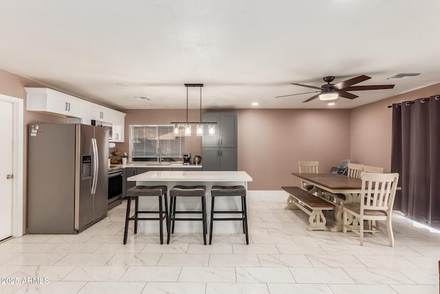 kitchen with stainless steel refrigerator with ice dispenser, sink, pendant lighting, a center island, and white cabinetry