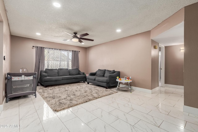 living room featuring ceiling fan and a textured ceiling