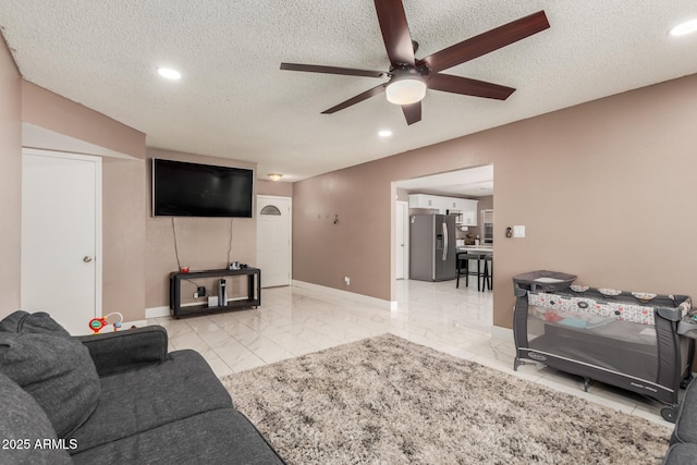 living room featuring ceiling fan and a textured ceiling