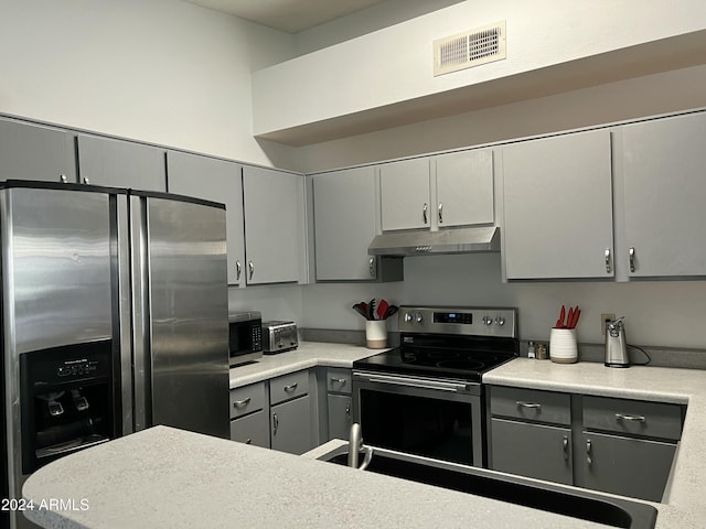 5839 E Norwood St, Mesa, AZ 85215 - kitchen with under cabinet range hood, visible vents, light countertops, gray cabinetry, and appliances with stainless steel finishes