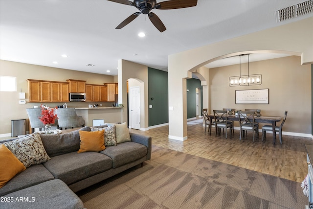 living room with ceiling fan with notable chandelier and light hardwood / wood-style floors