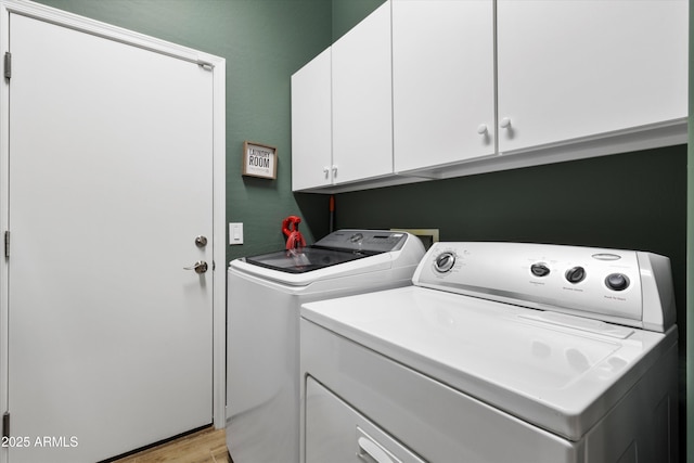 washroom featuring washer and dryer, cabinets, and light hardwood / wood-style flooring