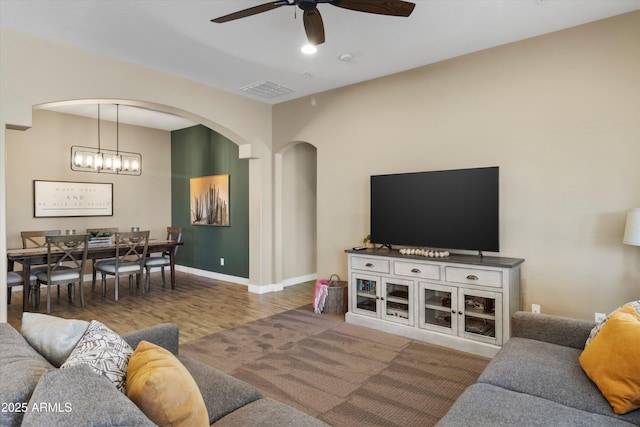 living room with hardwood / wood-style floors and ceiling fan with notable chandelier