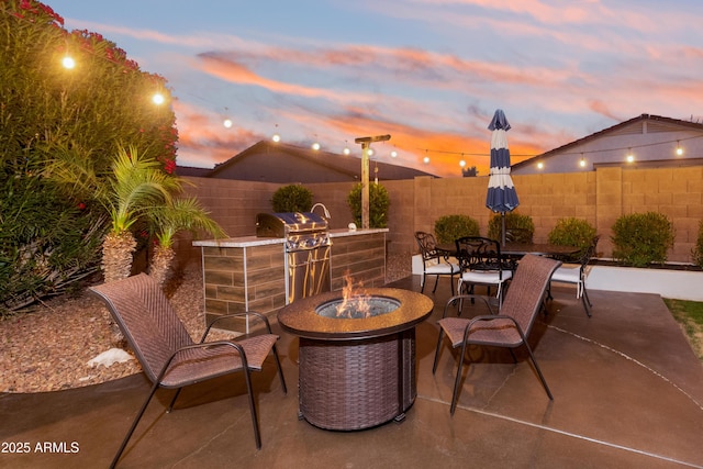 view of patio / terrace featuring a fenced backyard, outdoor dining area, an outdoor fire pit, and area for grilling