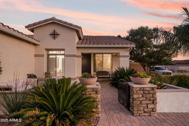 exterior space with a tiled roof, fence private yard, and stucco siding