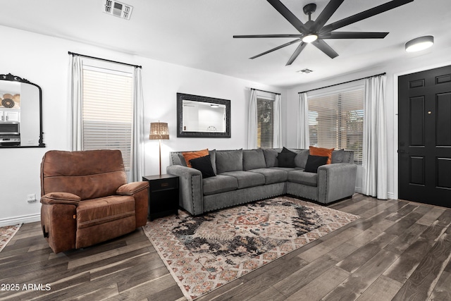living area featuring visible vents, a ceiling fan, baseboards, and dark wood-type flooring