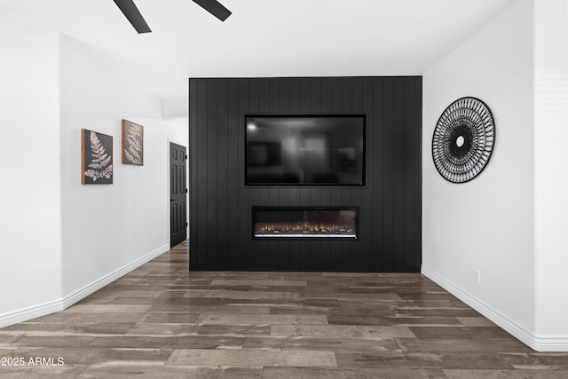 unfurnished living room featuring baseboards, a ceiling fan, a large fireplace, and wood finished floors